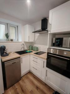 a kitchen with white cabinets and stainless steel appliances at Appartements à Evron in Évron