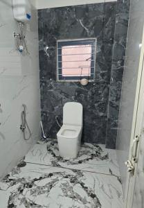 a bathroom with a toilet with a marble floor at SS Hostel in Siliguri +2 photos