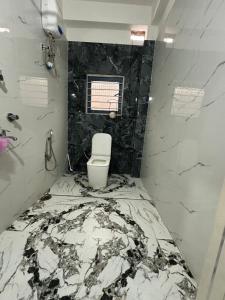 a bathroom with a white toilet and black marble walls at SS Hostel in Siliguri