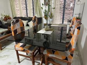 a dining room table with chairs and a glass top at SS Hostel in Siliguri