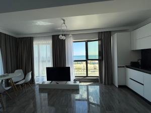 a living room with a large window and a television at Seaside Escape - Luxury Apartment in Năvodari