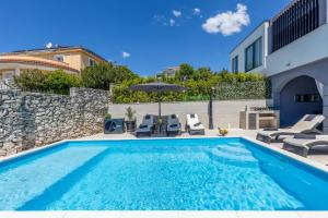 a pool with chairs and an umbrella next to a building at Villa Paula s grijanim bazenom in Crikvenica