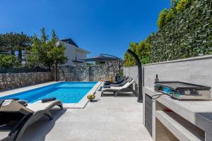 a swimming pool in a backyard with chairs and an umbrella at Villa Paula s grijanim bazenom in Crikvenica
