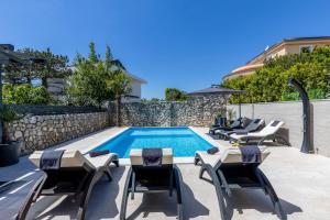 a swimming pool with chaise lounge chairs and a swimming pool at Villa Paula s grijanim bazenom in Crikvenica