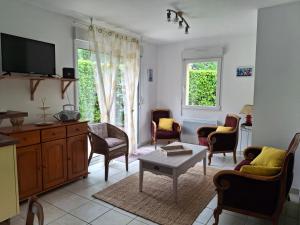 a living room with chairs and a tv and a table at Le Cocon Breton in Trébeurden