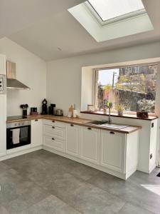 a white kitchen with a sink and a window at Superbe appartement avec jacuzzi et jardin privé in Marlhes