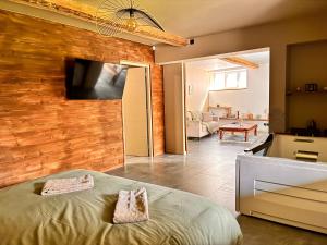 a bedroom with a wooden wall with a flat screen tv at Superbe appartement avec jacuzzi et jardin privé in Marlhes