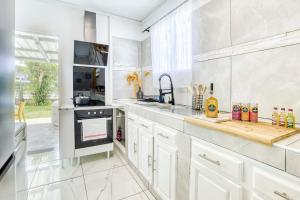 a white kitchen with a sink and a stove at La Villa Des Lys avec jacuzzi in Saint-Denis