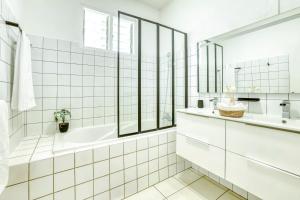 a white bathroom with a tub and a sink at La Villa Des Lys avec jacuzzi in Saint-Denis