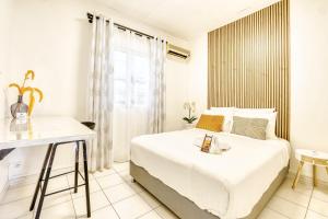 a white bedroom with a bed and a desk at La Villa Des Lys avec jacuzzi in Saint-Denis +29 photos
