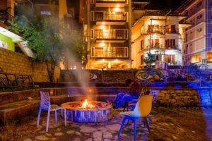 a man sitting in front of a fire pit with chairs at The Royal Pinewood in Kasol