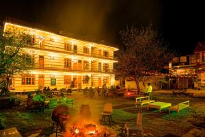 a building with a fire in front of it at night at The Royal Pinewood in Kasol