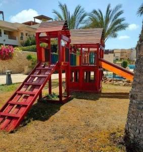 a playground with a slide and a play house at شالية ديمورا للعائلات in Dawwār Muḩammad Abū Shunaynah