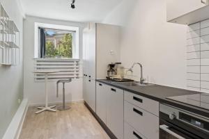 a kitchen with white cabinets and a sink and a table at John F Kennedys Suite in Aalborg