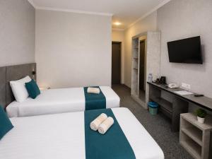 a hotel room with two beds and a television at Boston Hotel Tashkent in Yakkasaray