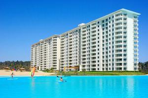 un gran edificio blanco con gente en tablas de surf en el agua en Departamento Laguna Bahia, en Algarrobo