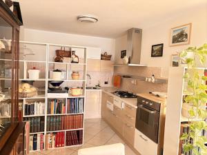 a kitchen with a book shelf filled with books at Casa di Paola Spormaggiore in Spormaggiore