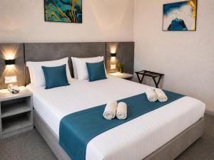 a bedroom with a large white bed with blue accents at Boston Hotel Tashkent in Yakkasaray