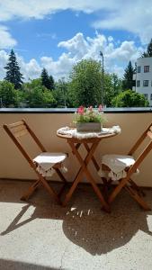 a table and two chairs on a balcony with flowers at Csilla Home Apartman in Miskolc