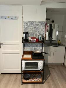 a small kitchen with a microwave on a cart at La chambre de la maison bleue in Colmar