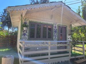 a tiny house with a porch and a window at Căsuța Vesela in Cernişoara
