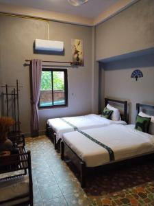 a bedroom with two beds and a window at Vinla Guesthouse & Backpackers Hostel in Nongkhiaw