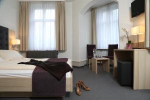 ein Hotelzimmer mit einem Schlafzimmer mit Bett und Schreibtisch in der Unterkunft Hotel Lötschberg in Interlaken