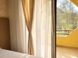 ein Schlafzimmer mit einem Fenster und einem weißen Vorhang in der Unterkunft Blue Mill Resort, Sarande in Mesopotam