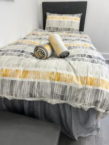 a bed with a gray and yellow comforter and pillows at Central Kettering Apartment by SJP Ideal for up to 3 Guests in Kettering