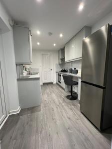 a kitchen with white cabinets and a stainless steel refrigerator at Central Kettering Apartment by SJP Ideal for up to 3 Guests in Kettering