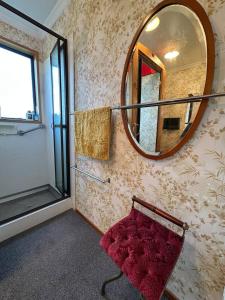 a bathroom with a mirror and a red bench at Kakanui Surf Bach in Kakanui