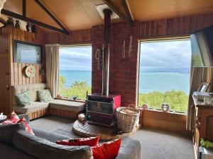 a living room with a fireplace and a view of the ocean at Kakanui Surf Bach in Kakanui