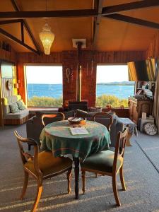 a living room with a table and chairs and a couch at Kakanui Surf Bach in Kakanui +10 photos