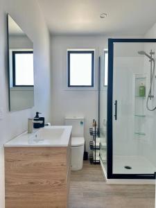 a white bathroom with a sink and a shower at Settlers Nook Oamaru in Oamaru