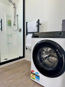 a washing machine in a bathroom with a shower at Settlers Nook Oamaru in Oamaru