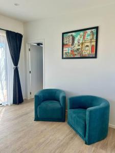 a living room with two blue chairs and a painting at Settlers Nook Oamaru in Oamaru