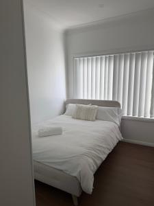 a bed in a white room with a window at Second Home - A modern 4 Bedrooms House in Blacktown +2 photos