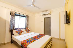 a bedroom with a bed and a window and a television at FabHotel Ateethi Residency in Pune