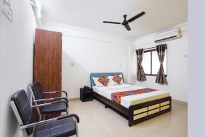 a bedroom with a bed and two chairs in it at FabHotel Ateethi Residency in Pune