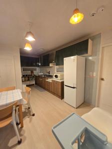 a kitchen with a table and a white refrigerator at 홍쓰 오션뷰 in Hakch'ŏn-dong +11 photos