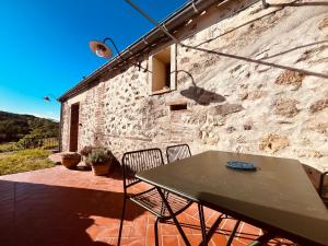 a table and chairs on a patio with a stone wall at Mas Saint Michel in Vivès