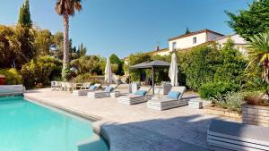 a pool with lounge chairs and umbrellas next to a house at Casa Dina in Sommières