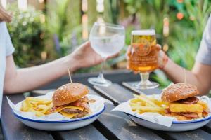 a table with two sandwiches and french fries and a glass of beer at The Pelican Inn in Stapleford