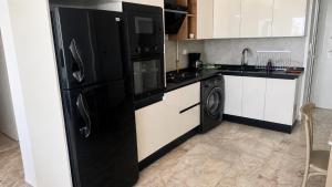 a kitchen with black appliances and a black refrigerator at Penthouse sarra in Kelibia
