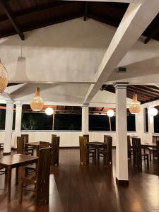 a dining room with wooden tables and chairs and chandeliers at Polhena Neptune Resort in Matara