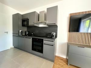a kitchen with gray cabinets and a stove top oven at apments - Premium Apartments nahe Hamburg in Rosengarten