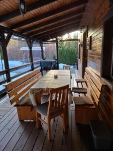 a wooden deck with a wooden table and benches at Ezüst fenyő vendégház in Borzont