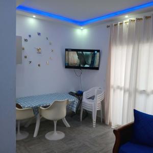 a room with a table and chairs and a tv on the wall at Littlhouse in Rafrāf