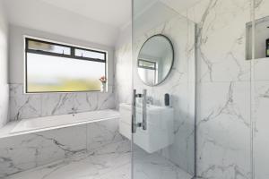 a white bathroom with a sink and a mirror at McLaren Lake View in Tauranga +69 photos