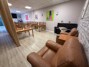 a waiting room with a leather couch and tables and chairs at COLIBRI in Calella +96 photos